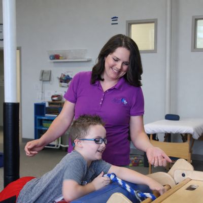 An occupational therapist working with a boy on a hands-on tabletop activity