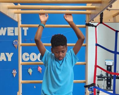 A boy stretching up on a climbing wall in the therapy gym